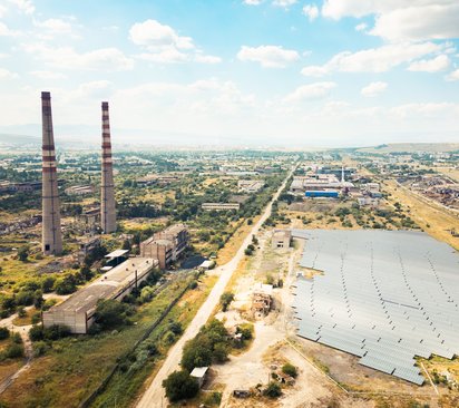 Umwelt & Umwelttechnik - Solarkraftwerk Überflug eines Solarkraftwerks oder -bauernhofs in der Nähe eines verlassenen Industriekomplexes in Rustavi, Georgien, der den Kontrast zwischen dem Fortschritt der erneuerbaren Energien und dem verfallenden umweltschädlichen Erbe veranschaulicht