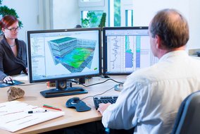 Mann sitzt vor dem Computer. Auf dem Bildschirm ist eine 3D Grafik.