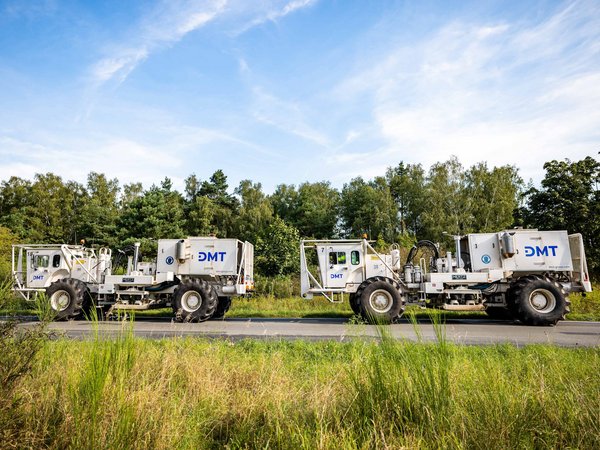 DMT-Vibrotrucks bei der seismischen Standorterkundung in einer grünen Landschaft