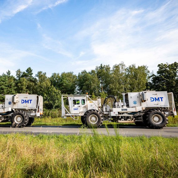 DMT-Vibrotrucks DMT-Vibrotrucks bei der seismischen Standorterkundung in einer grünen Landschaft