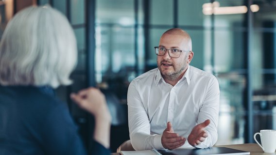 Geschäftsmann im Gespräch Geschäftsmann im Gespräch mit einer Managerin in einem Büro am Schreibtisch