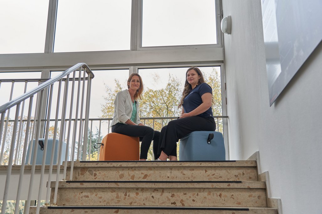 Cherine Nickel und Natalie Morris im Treppenhaus auf Sitzhockern