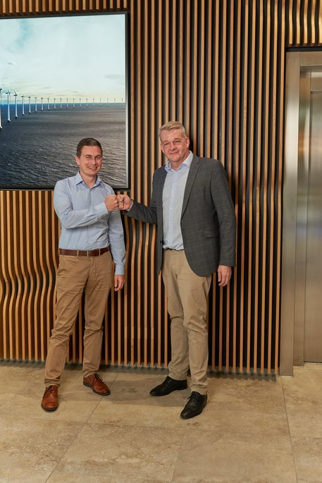Carsten Gelhard und Knur Hirsch stehen vor einer Wand mit Holzelementen