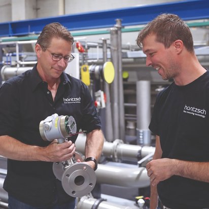 Mitarbeitende bei Höntzsch Zwei männliche Mitarbeitende bei Höntzsch, einer der beiden hält ein Präzisionsinstrument zur Strömungsmesstechnik