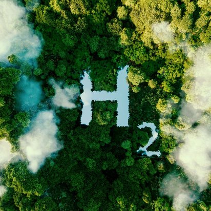 Grüner Wald Luftaufnahme eines dichten, grünen Waldes, durch den Nebel oder Wolken ziehen. In der Mitte des Waldes ist ein See oder eine Wasserfläche in Form des chemischen Symbols „H₂“