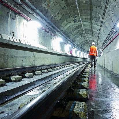 Tunnelinfrastruktur Ein Ingenieur ist von hinten in einem hell erleuchteten Betontunnel zu sehen
