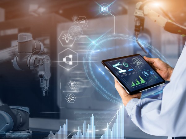 Symbolbild zum Thema Transparenz in der Produktion: Ingenieur hält ein Notebook, auf dem Monitoringwerte der überwachten Maschine erscheinen.