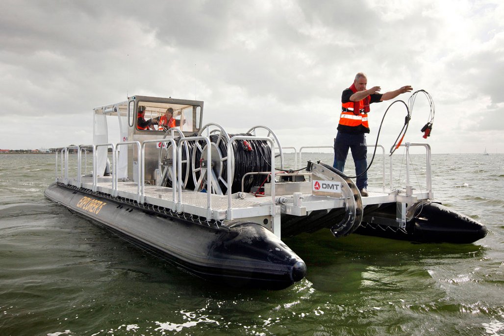Mann steht auf Boot und wirft Kabel ins Wasser