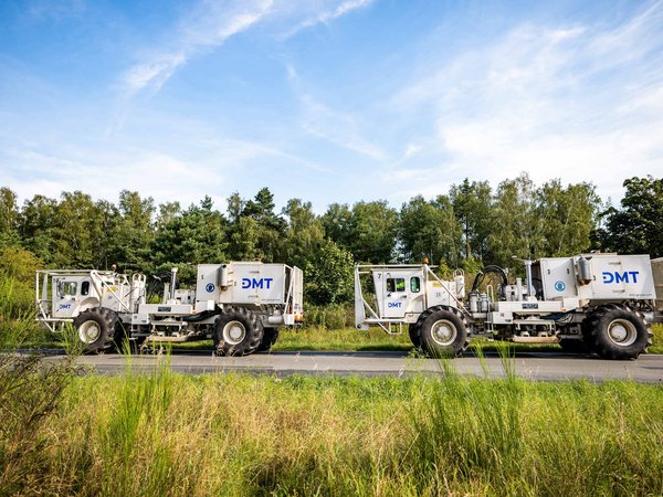 DMT-Vibrotrucks bei der seismischen Standorterkundung in einer grünen Landschaft