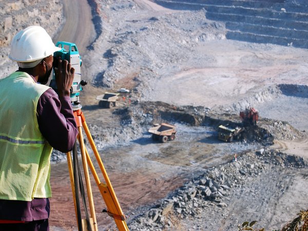 Symbold für die Geologische Modellierung von Lagerstätten: Ingenieur nutzt ein Vermessungsgerät in einem Tagebau