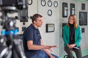Andre Lüttmann und Natalie Morris sitzen auf einem Hockern