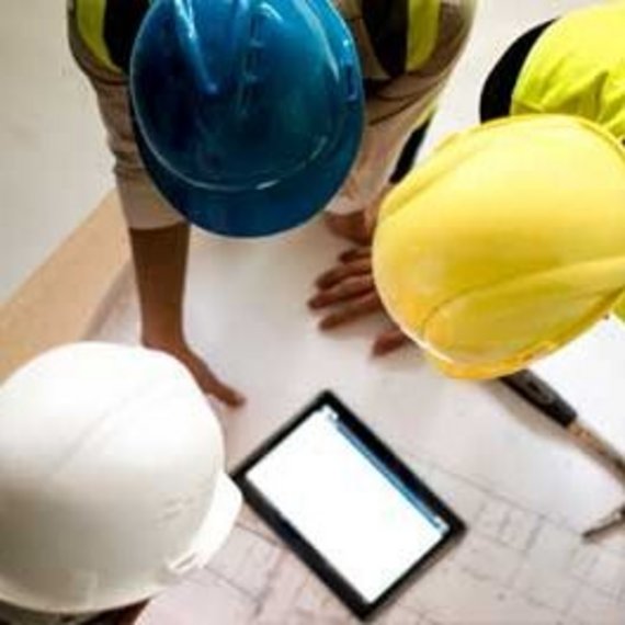 Feldarbeiter nutzt Technologie für das Projektmanagement Person in Warnweste und Schutzhelm, kniend und ein Tablet im Freien benutzend