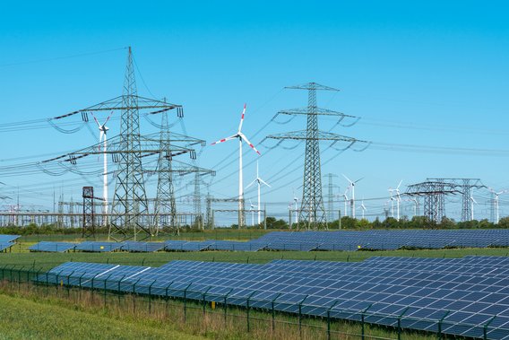 Energieerzeugung Symbolbild Energieerzeugung: Strommasten, Windräder und Solarpaneneele auf grüner Wiese