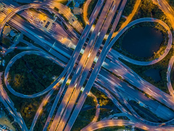 Luftaufnahme eines komplexen Autobahnkreuzes bei Nacht.