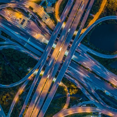 Luftaufnahme eines komplexen Autobahnkreuzes bei Nacht.