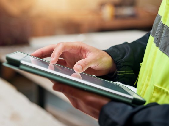 Mann hält ein Notebook und streicht mit seinen Fingern über die Arbeitsoberfläche
