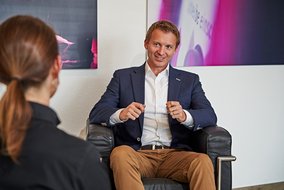 Roman Krähling und Natalie Morris sitzen vor einer Wand in Sesseln.