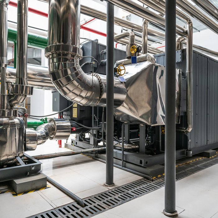 Lithiumbromid-Absorptionswärmepumpe in industrieller Anlage mit zahlreichen glänzenden, metallischen Rohrleitungen und Ventilen.