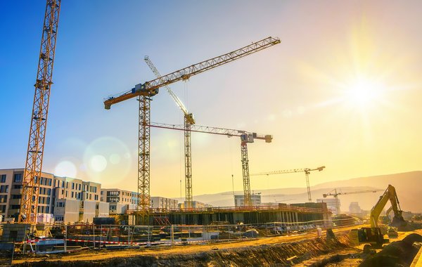 Großbaustelle | Bauwesen und Infrastruktur Baukräne im Abendlicht auf einer Großbaustelle; Symbolbild für den Bereich Bauwesen und Infrastruktur