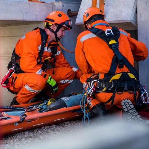 Zwei Mitglieder eines Rettungsteams knien neben einer Trage während einer Einsatzübung