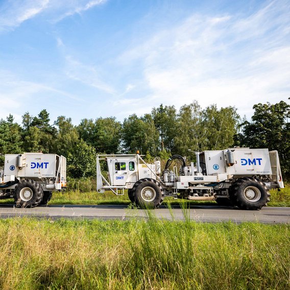 DMT-Vibrotrucks bei der seismischen Standorterkundung in einer grünen Landschaft