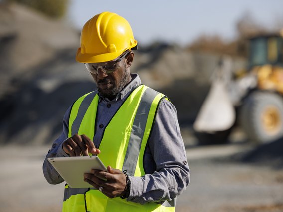 Due Diligence Prüfungen Symbolbild Due Diligence Prüfungen: Porträt eines Ingenieurs mit Schutzhelm mit digitalem Tablet bei der Arbeit auf der Baustelle
