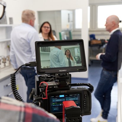 Melanie Wiegand und Knut Hirsch beim Interview Melanie Wiegand und Knut Hirsch beim Interview, Foto hinter den Kulissen mit sichtbarer Kamera zwischen den Takes