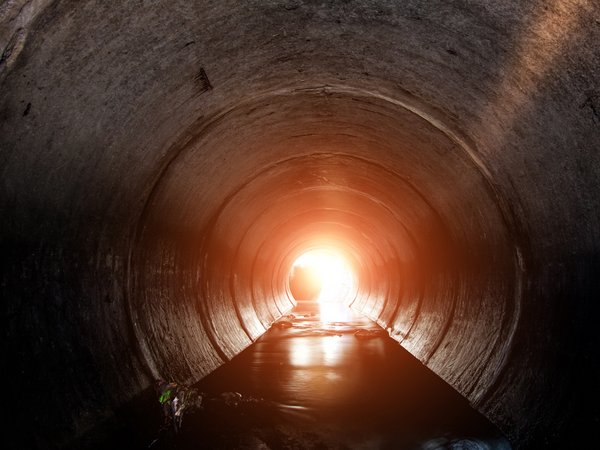 Lüftung Abwassernetze & Kanalbetrieb: Blick in einen Abwasserkanal, der etwas Wasser führt.