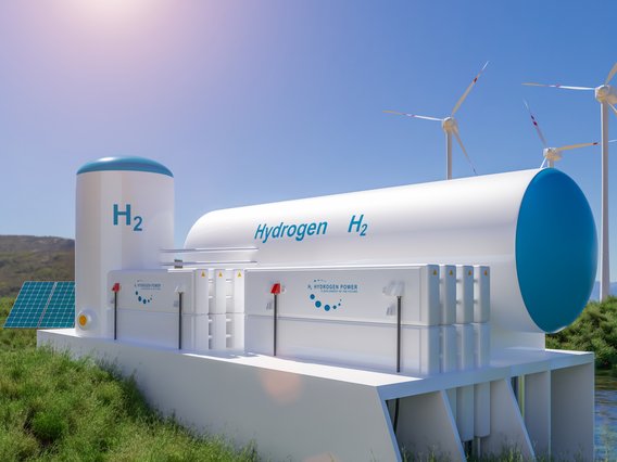 Wasserstoffanlage_H2-Tanks_Wind_PV Wasserstoffanlage in einer natürlichen Umgebung. Im Vordergrund sind große Tanks mit der Aufschrift „H₂ Hydrogen zero emission“ zu sehen.