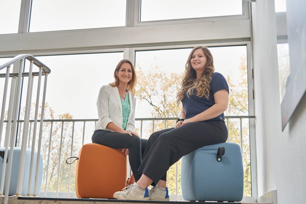 Cherine Nickel und Natalie Morris im Treppenhaus auf Sitzhockern