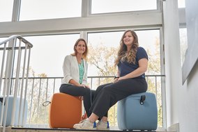 Cherine Nickel und Natalie Morris im Treppenhaus auf Sitzhockern