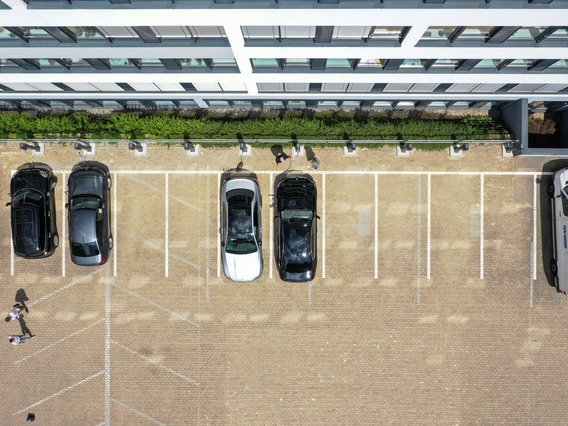 Luftaufnahme eines Parkplatzes neben einem modernen Gebäude. 