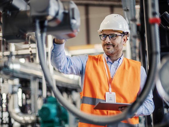 Ein Ingenieur mit Schutzhelm prüft eine Maschine in einer Fabrik