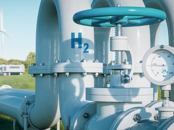 Wasserstoffpipeline Große, silberne Pipeline mit einem Ventil und einem Druckmesser im Vordergrund.