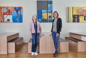 Mary Anderson und Natalie Morris stehen vor einem Tisch mit zwei Bänken