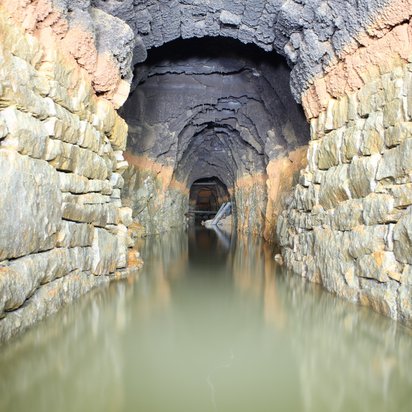 Wassergefüllter Altbergbaustollen Blick in einen wassergefüllten Altbergbaustollen, das Wasser steht etwa bis zu einer Höhe von einem Meter.
