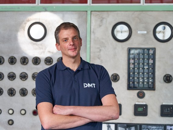 André Lüttmann Foto von André Lüttmann aus dem Bereich Monitoring und Data Engineering bei DMT vor einem Maschinenschaltschrank