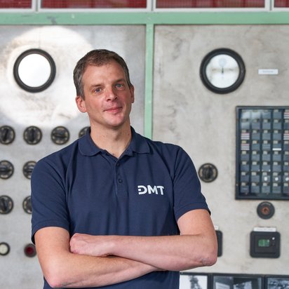 André Lüttmann Foto von André Lüttmann aus dem Bereich Monitoring und Data Engineering bei DMT vor einem Maschinenschaltschrank