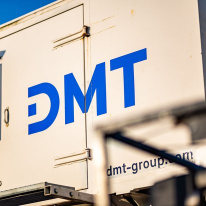 Vibrotruck der DMT GROUP Foto vom Heck eines Vibrotrucks, mit dem blauen Logo von DMT