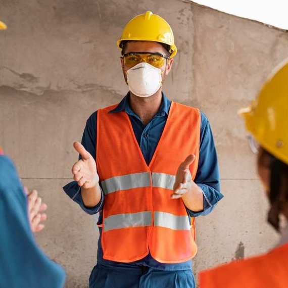 Professionelle Diskussion über Sicherheit und Zusammenarbeit Zwei Arbeiter in Warnwesten und Schutzhelmen, die sich in ein Gespräch vertieft sind