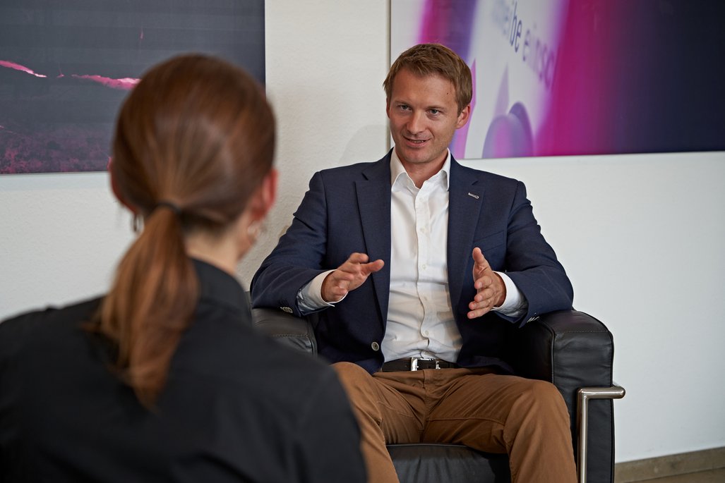 Roman Krähling und Natalie Morris sitzen vor einer Wand in Sesseln.