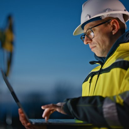 Digitale Transformation im Bergbau Ingenieur mit Laptop bei der Arbeit in der Abenddämmerung