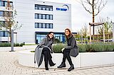 Was für uns spricht, sind unsere Mitarbeitenden 2 Frauen auf einer Bank vor der Zentrale der TÜV NORD GROUP in Essen